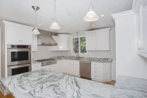 A bright white kitchen remodel with stone countertops by Biviano